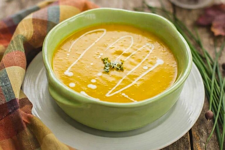 a bowl of Creamy Vegan Butternut Squash Apple Soup drizzled with coconut cream