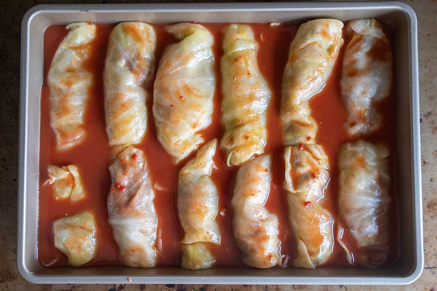 overview of beef cabbage rolls in a light tomato sauce layered in a baking pan