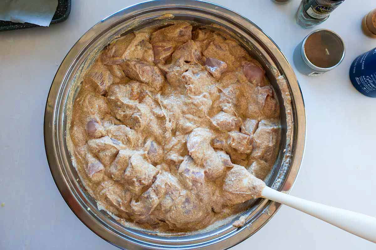 chicken marinating in a yogurt mixture with Indian spices