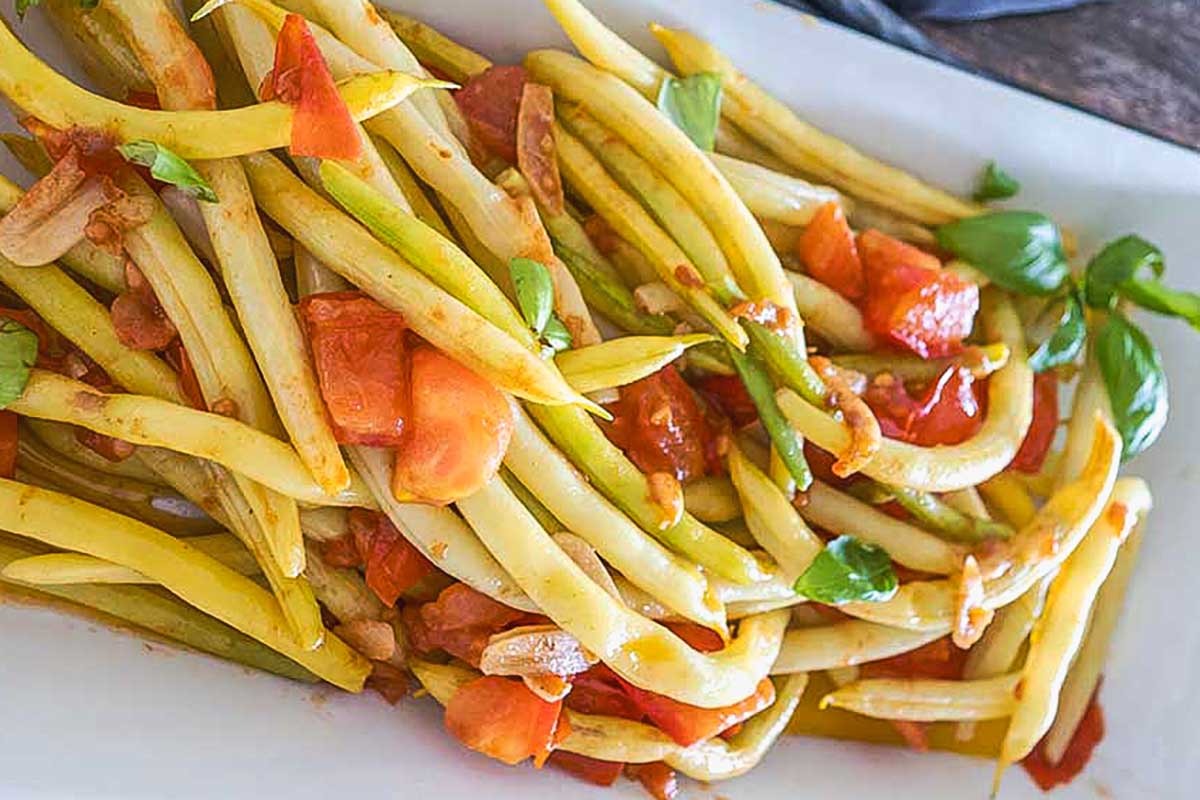close up of Greek-Style Yellow Beans with Garlic and Tomatoes on a white platter