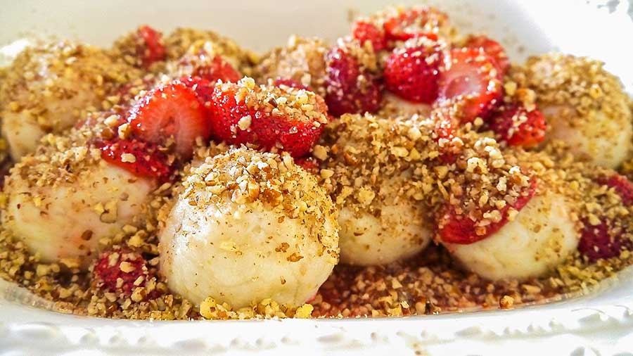 close up of strawberry dumplings with nut topping