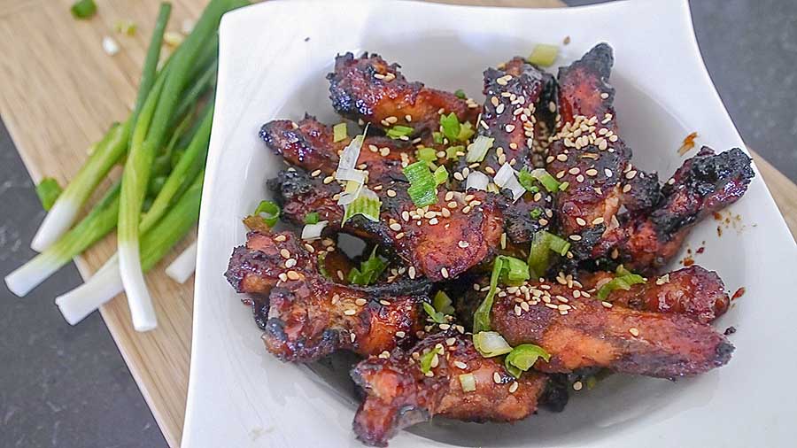 honey ginger wings topped with green onions on a plate