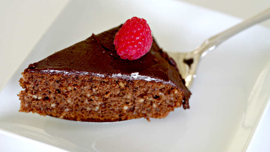 a slice of gluten free dairy free mocha walnut cake topped with a raspberry