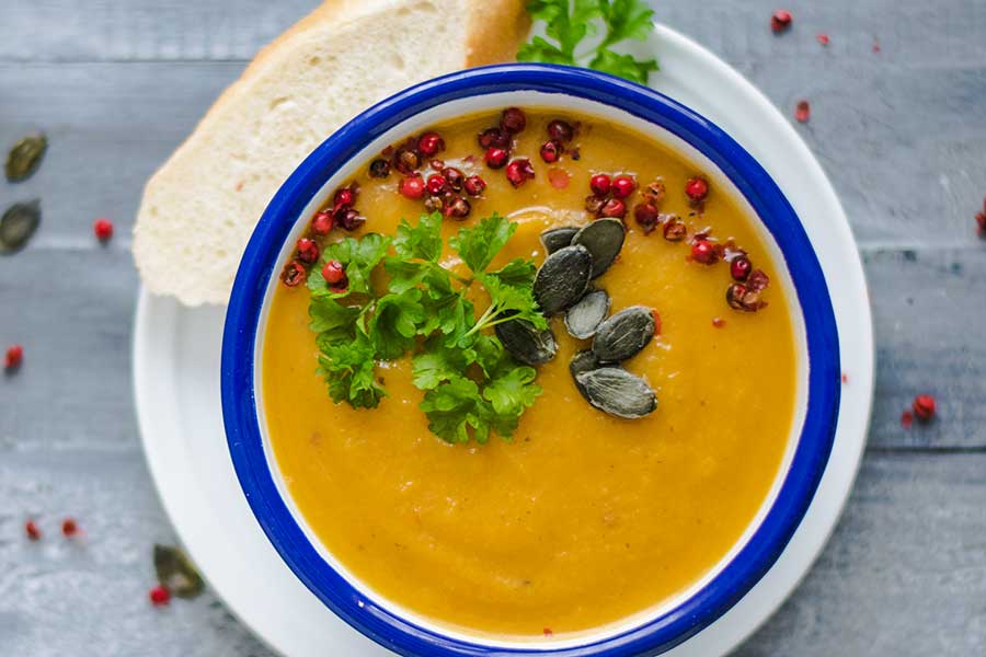 thai carrot soup in a bowl with toppings