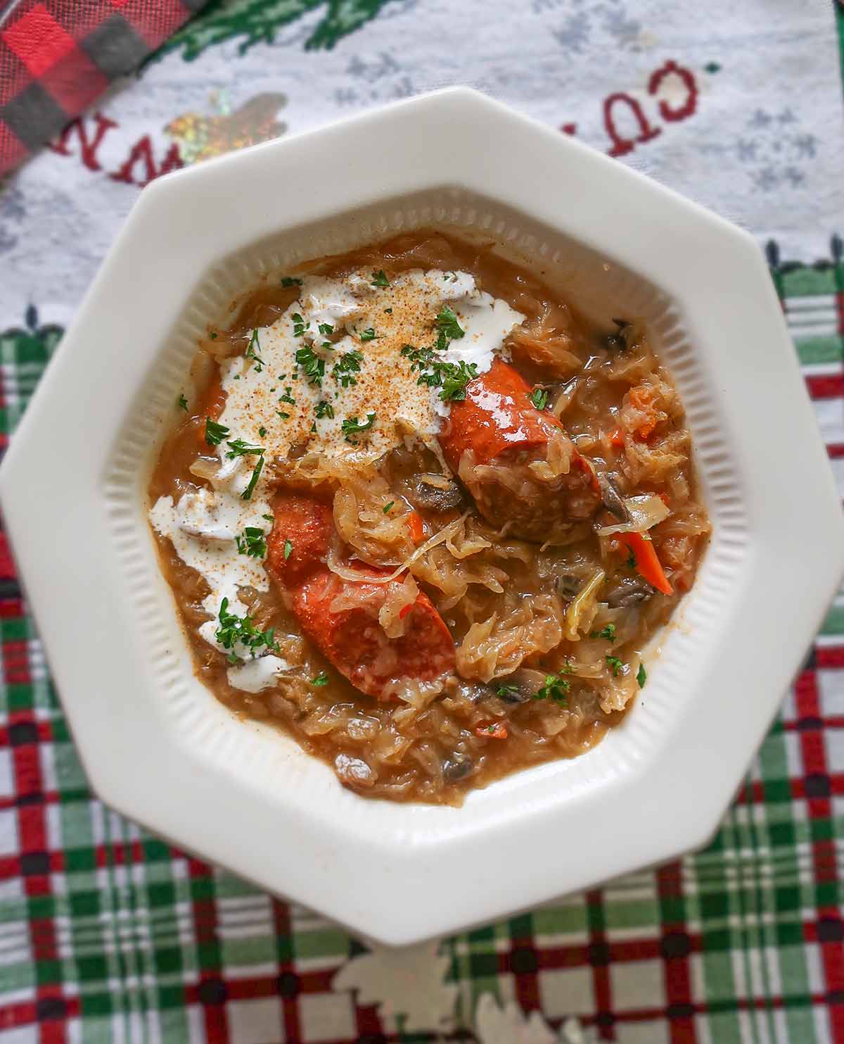 sauerkraut soup topped with sour cream and herbs in a bowl