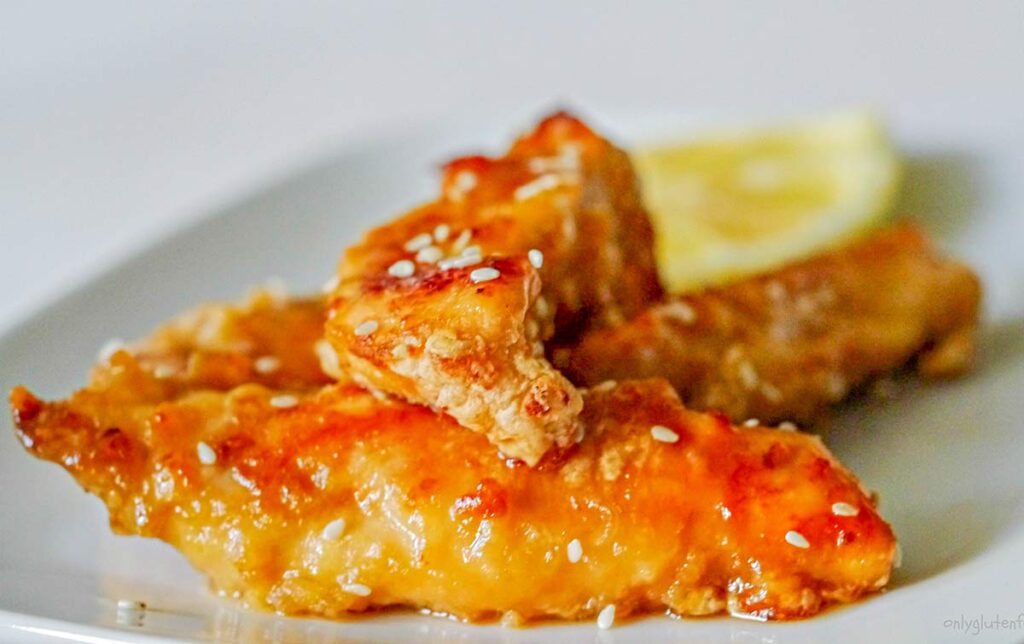 lemon chicken tenders on a plate with a slice of lemon