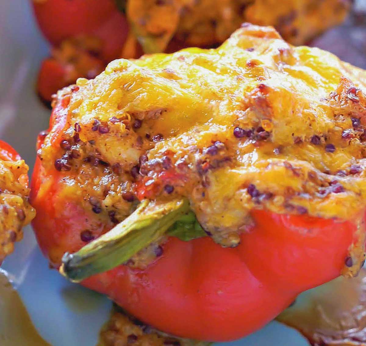 cheesy chicken stuffed red pepper with quinoa, sour cream, tomatoes and topped with melted cheddar