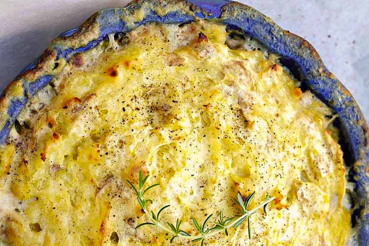 Golden, gluten-free chicken pot pie with a crispy potato crust, filled with chicken and vegetables, topped with rosemary and freshly cracked black pepper.