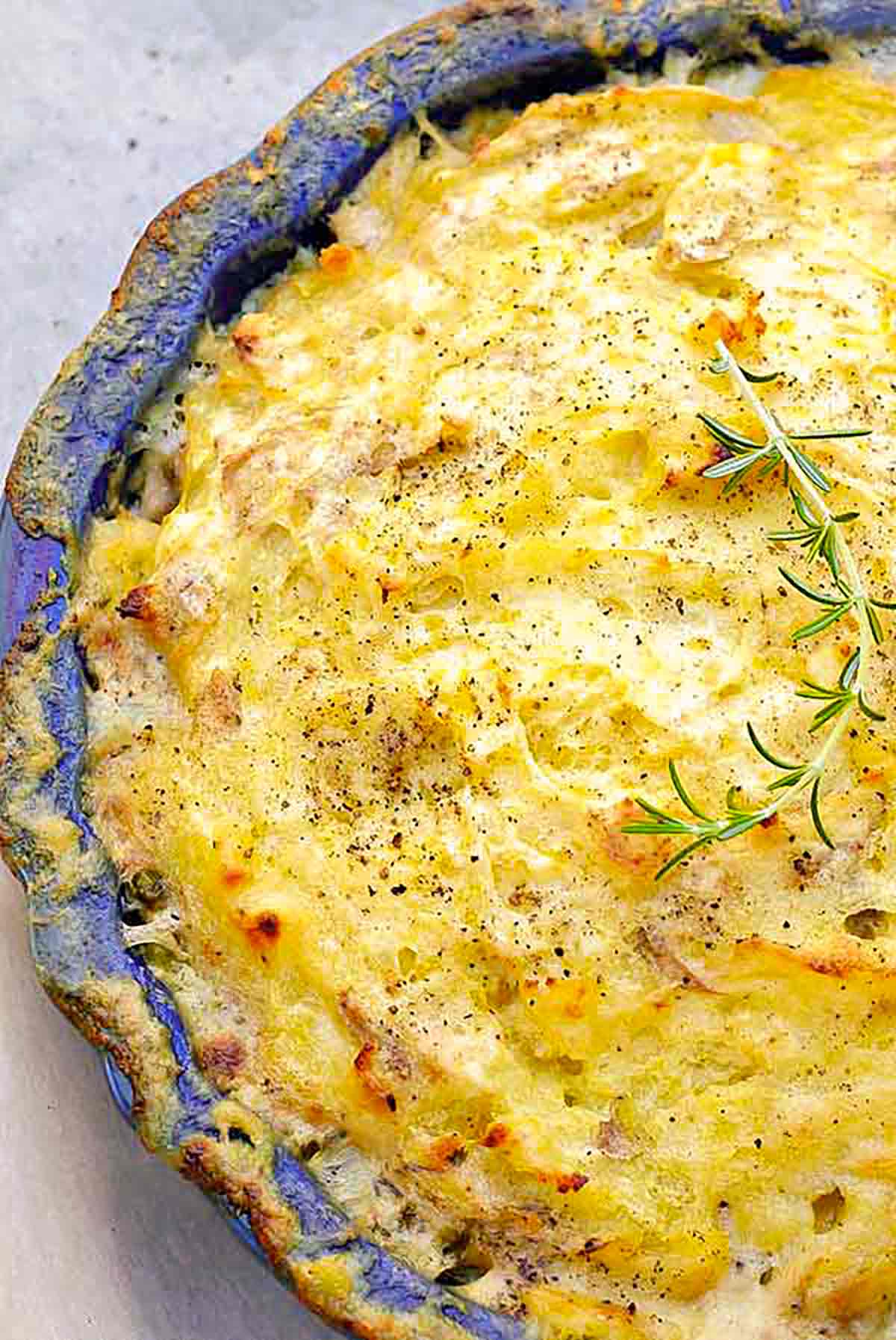 Gluten-free chicken pot pie with a golden, crispy potato crust, filled with chicken and vegetables, topped with fresh rosemary and cracked black pepper