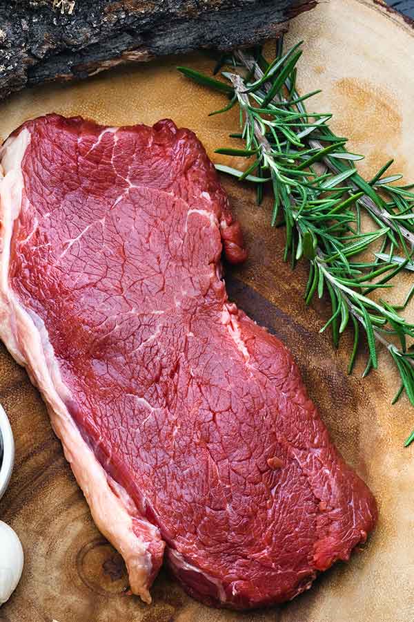 chuck steak with rosemary on a cutting board