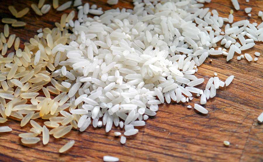 brown and white uncooked rice on a wooden board