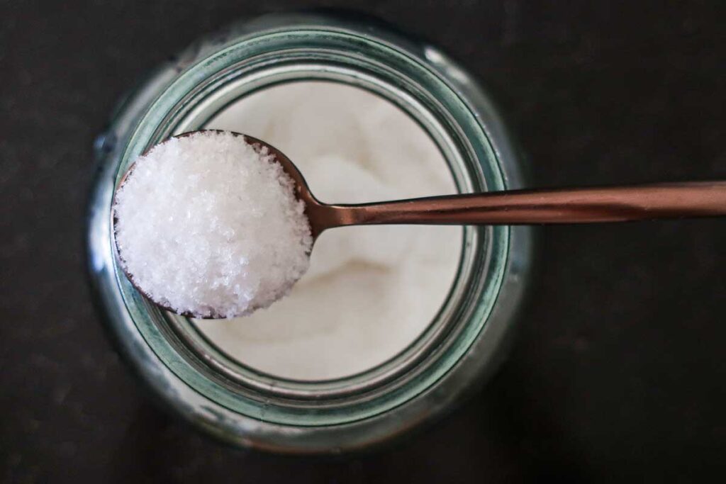 sea salt in a spoon over a glass jar