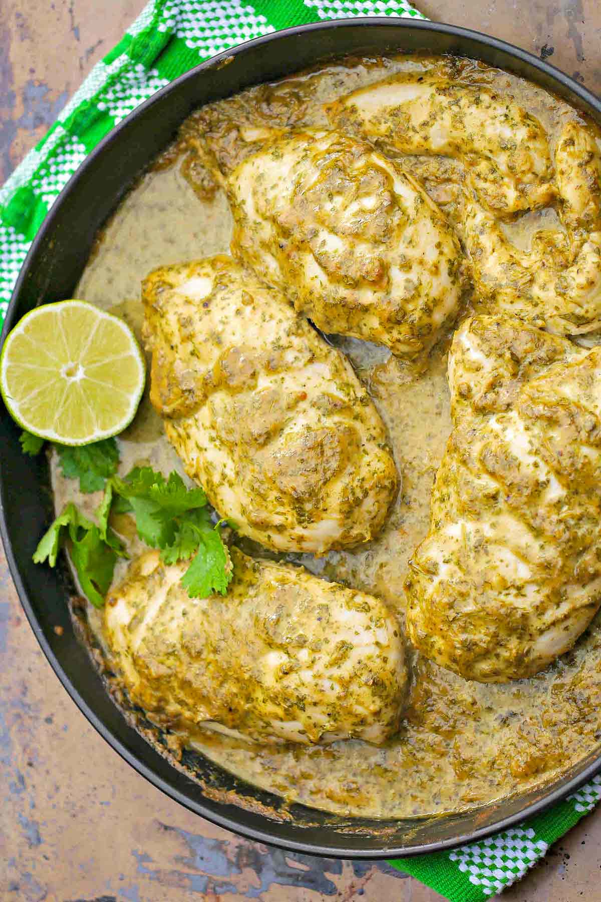 cilantro lime chicken in a skillet with limes and fresh cilantro