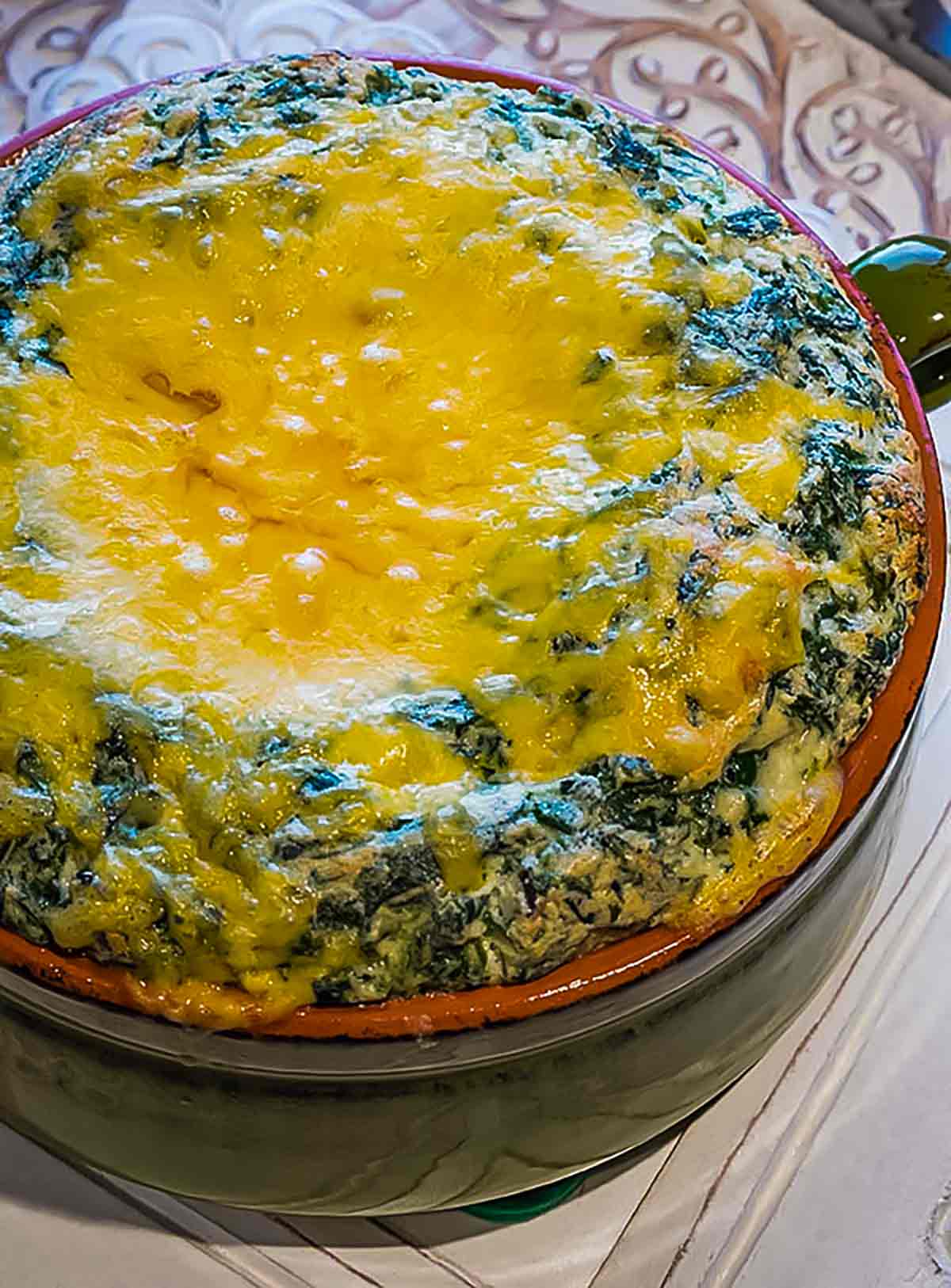 cheese spinach souffle in a green baking dish