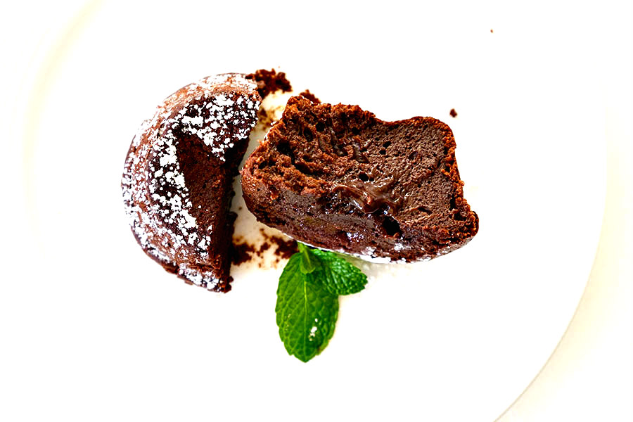 showing cross section of chocolate lava muffin with chocolate sauce in the middle