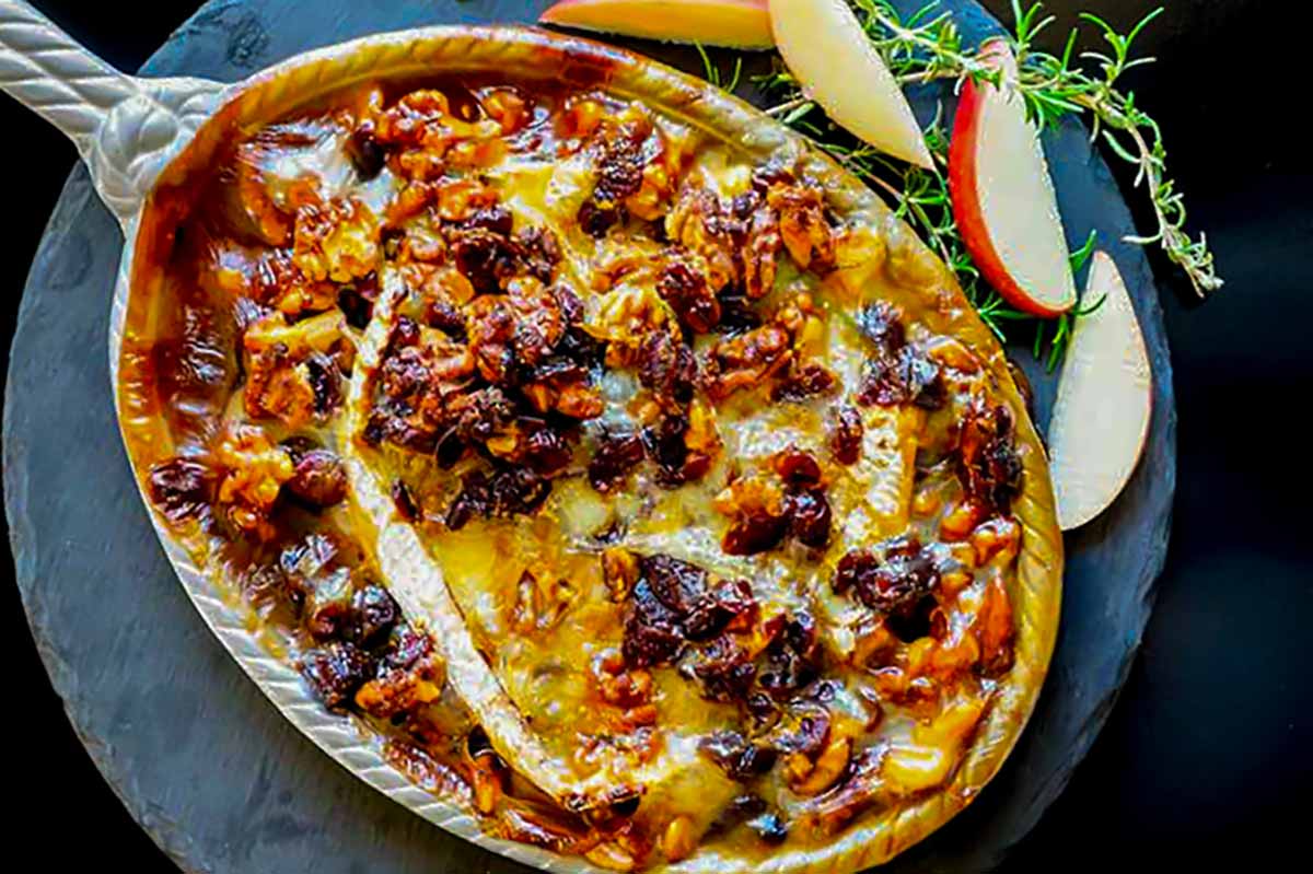 close up of hot goey Camembert cheese with toppings and Sid of fresh apple slices