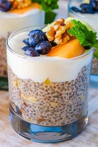 chia pudding with pineapple, dates in a cup and topped with walnuts and berries