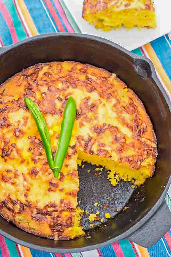 cheesy cornbread in a skillet missing a slice