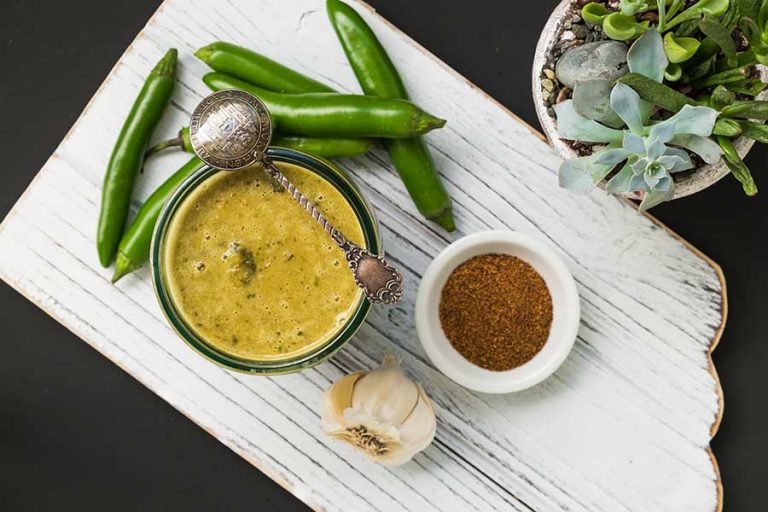 green enchilada sauce in a bowl with fresh jalapeno peppers on the side