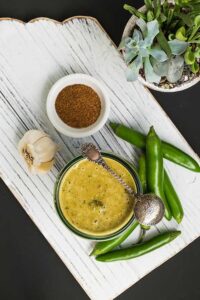 green enchilada sauce in a bowl with fresh jalapeno peppers on the side