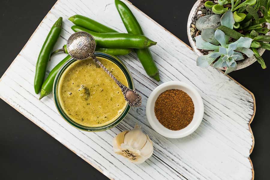 green enchilada sauce in a bowl with fresh jalapeno peppers on the side