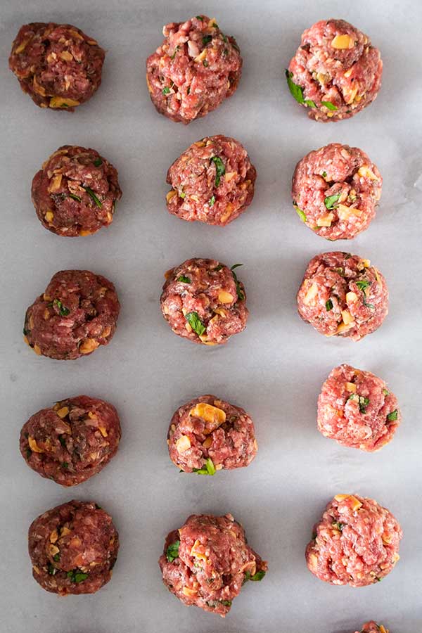 raw meatballs on a baking sheet line with parchment paper