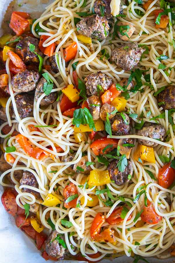 close up of spaghetti and meatballs with vegetables in a bowl