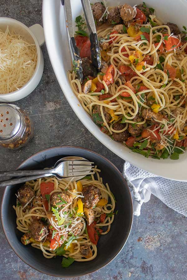 sheet pan spaghetti and meatballs in bowls topped with parmesan