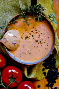 creamy Creole black bean soup in a bowl with a spoon topped with chili flakes