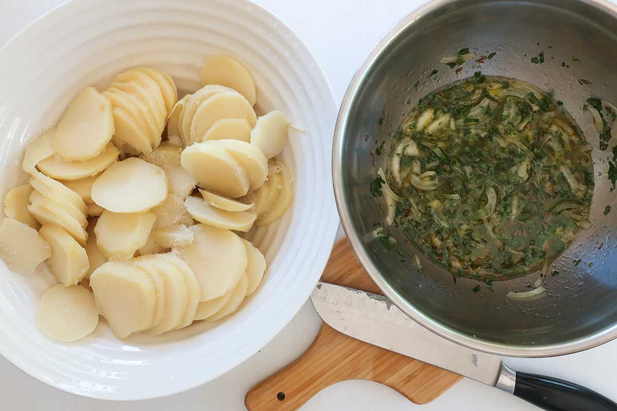 cooked sliced potatoes and light vinaigrette with caraway and fresh parsley in 2 bowls