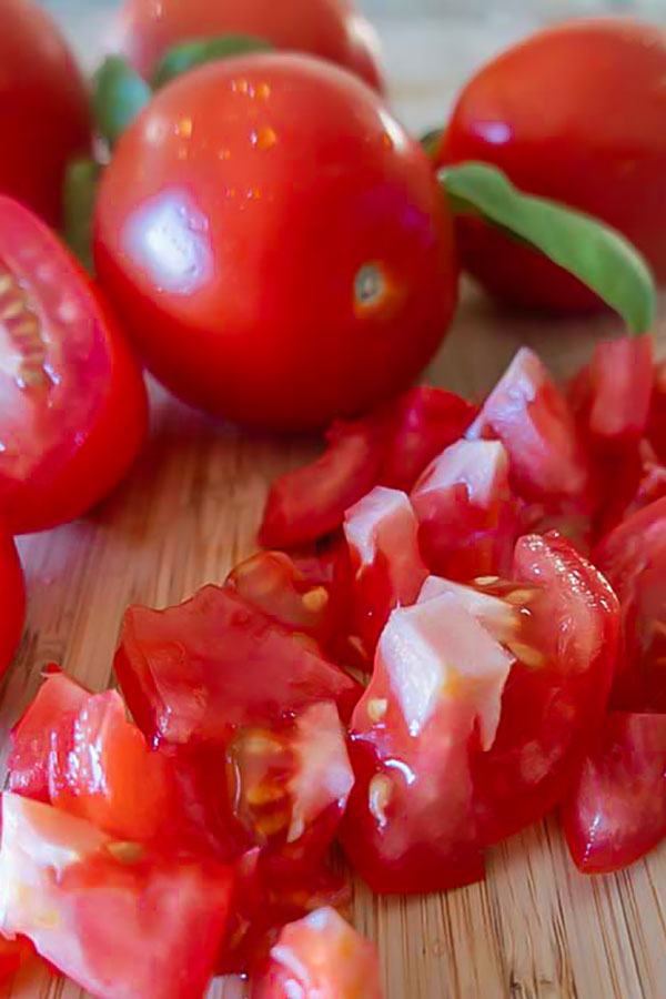 whole and chopped tomatoes on a cutting board