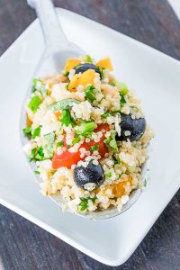 quinoa with feta, olives, tomatoes, peppers an onions salad on a plate