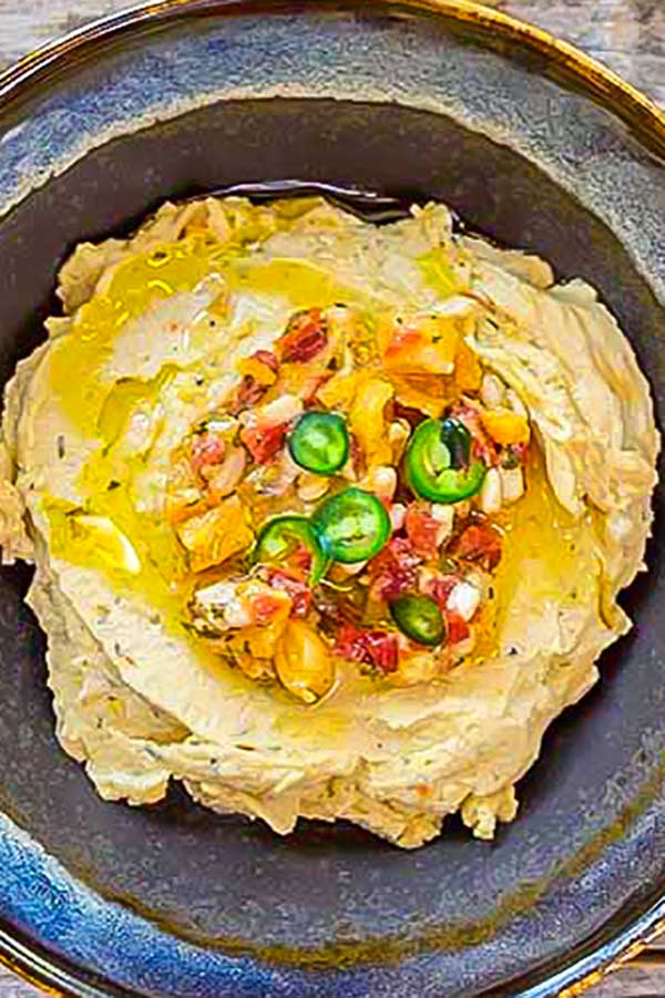 golden lentil hummus in a bowl with toppings