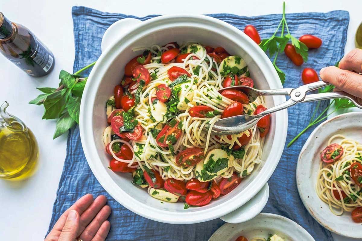 service marinated Italian pasta with bocconcini cherry tomatoes and fresh herbs in a salad bowl