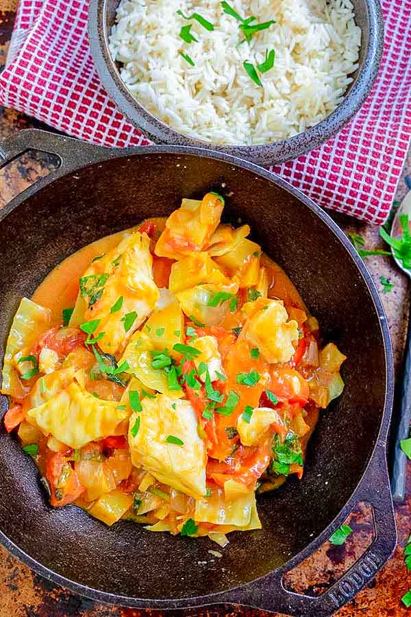 caribbean fish curry in a skillet with a side of rice