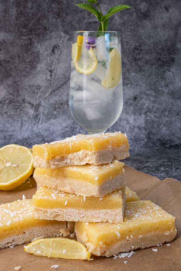 stacked vegan lemon coconut bars with glass of water