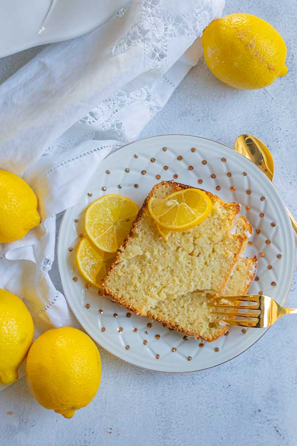 sliced ricotta lemon loaf on a plate with lemons