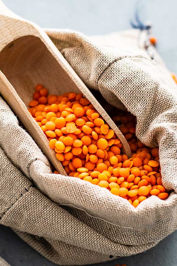 red lentils in a cloth sack with wooden spoon