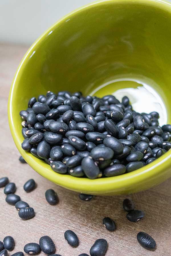 uncooked black beans in a green bowl