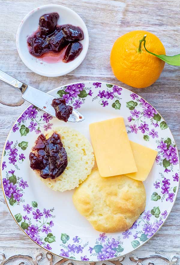 gluten free English muffin on a plate with cheese and jam
