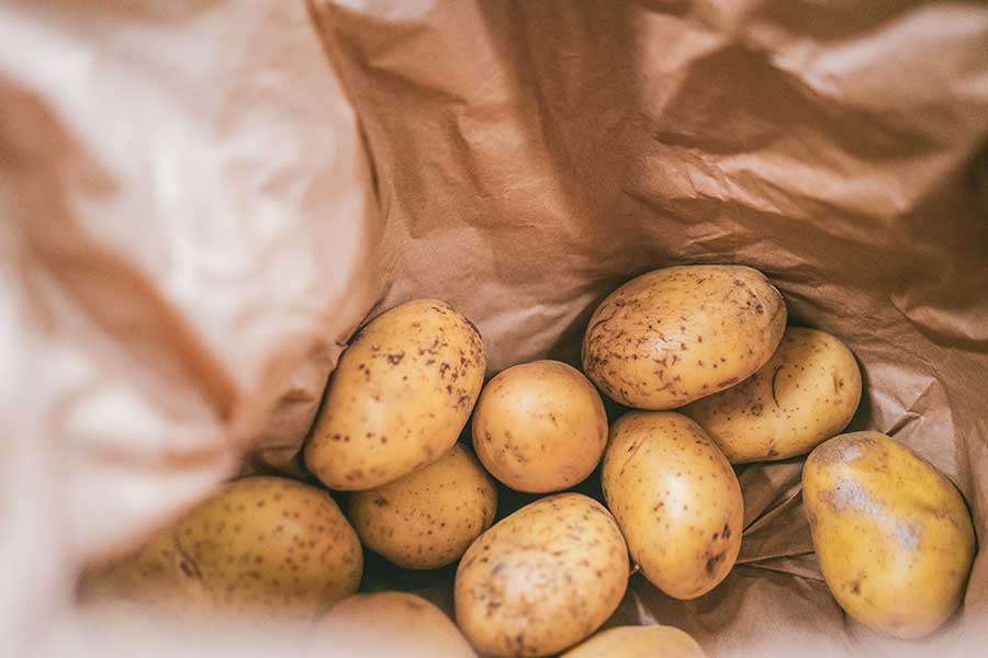 yellow raw potatoes in a paper bag