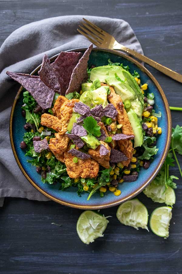 baja chicken kale salad with avocado and corn chips on a plate
