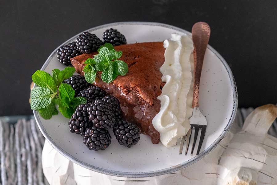 a slice of chocolate blackberry pie with whipped cream on a plate