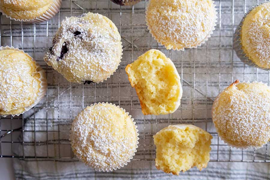 gluten free muffins on a cooling rack sprinkled with powdered sugar