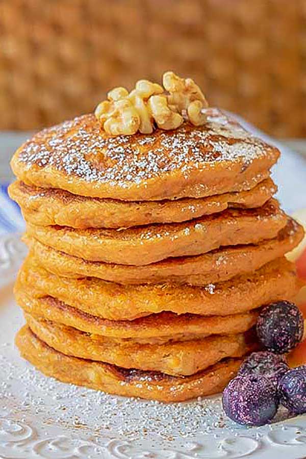 stacked carrot pancakes with walnuts and blueberries on a plate