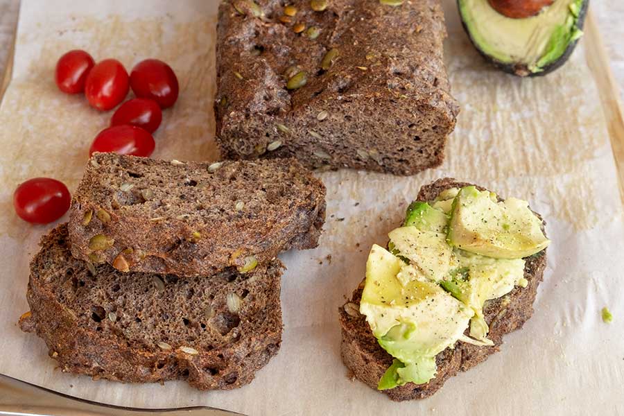sliced pumpkin seed bread topped with avocado