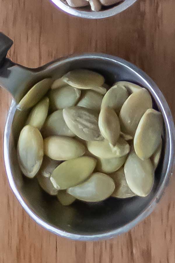 raw pumpkin seeds in a measuring cup