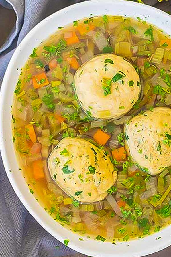 matzo ball soup in a bowl with herbs