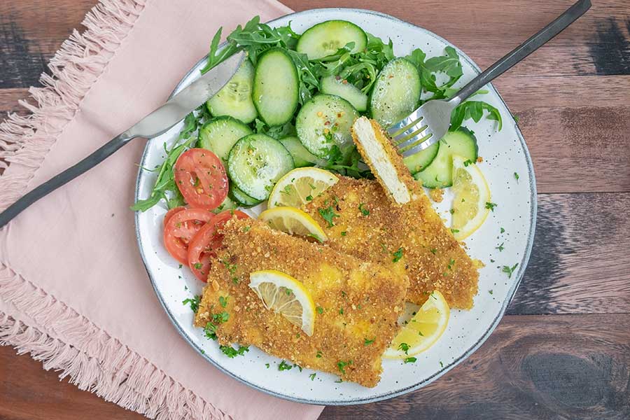 gluten free vegetarian schnitzel on a plate with cucumber salad