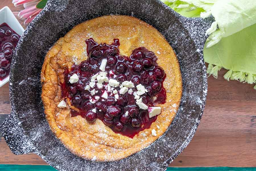 dutch baby made in a cast iron skillet with blueberry compote